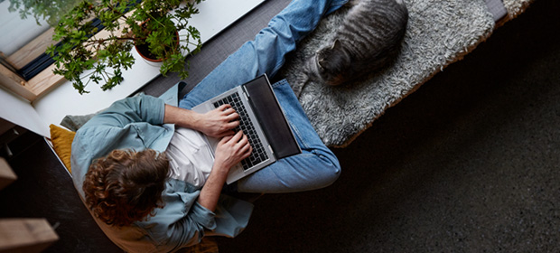 mann jobber på pc med en katt som sitter ved siden av