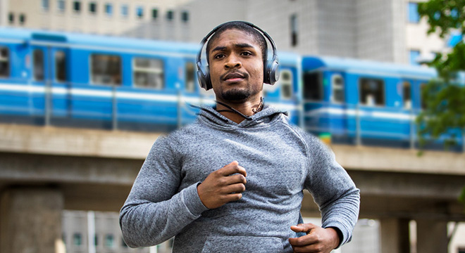 Ung mann løper i byen med hodetelefoner